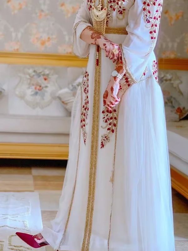 Femme portant un merveilleux caftan marocain ivoire à broderies florales bordeaux et dorées