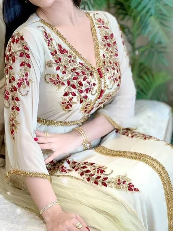 Une femme assise portant un caftan marocain ivoire à broderies florales 