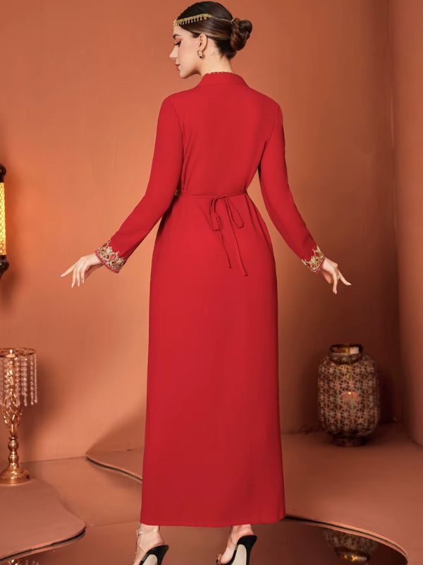 Vue de dos d'une femme portant un caftan marocain rouge, dévoilant la fluidité de la jupe et la ceinture dorée nouée dans le dos