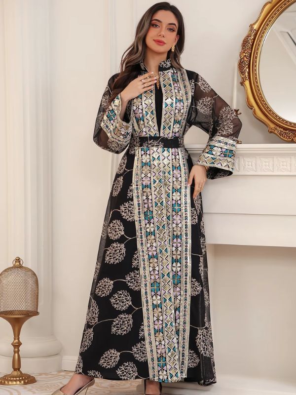 Femme portant un caftan marocain noir fleuri à broderies andalouses, dans un intérieur raffiné.