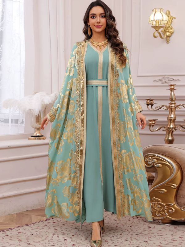 Femme portant un caftan marocain turquoise à motifs floraux dorés sur une robe assortie, dans un décor raffiné
