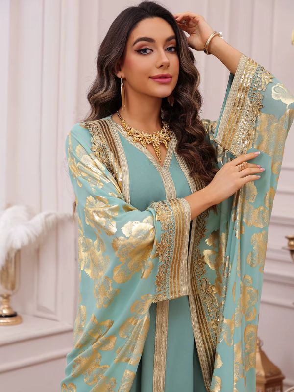 Vue rapprochée d'une femme en caftan turquoise à fleurs dorées, avec galons brodés or et collier doré