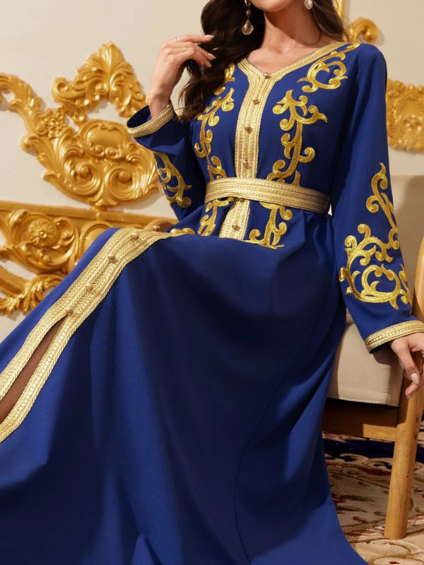Gros plan sur un caftan bleu royal aux broderies dorées et à la fente latérale, ceinturé de galon doré