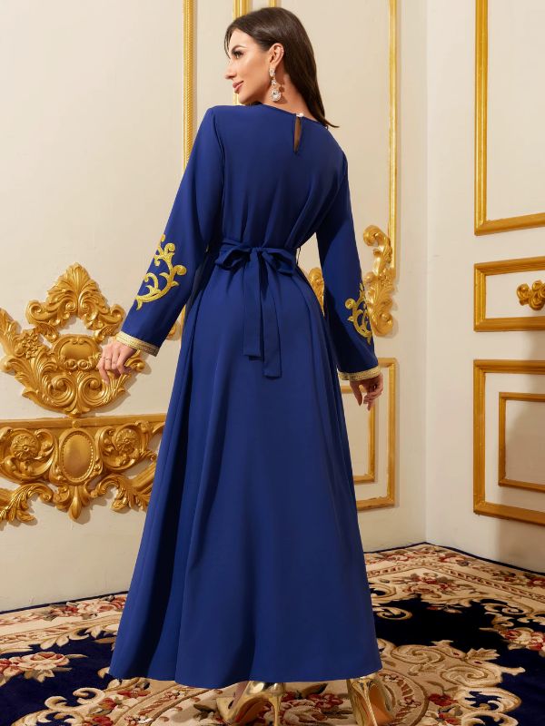 Femme en caftan marocain bleu royal vu de dos, ceinture nouée et broderies dorées sur les manches, dans un décor doré raffiné
