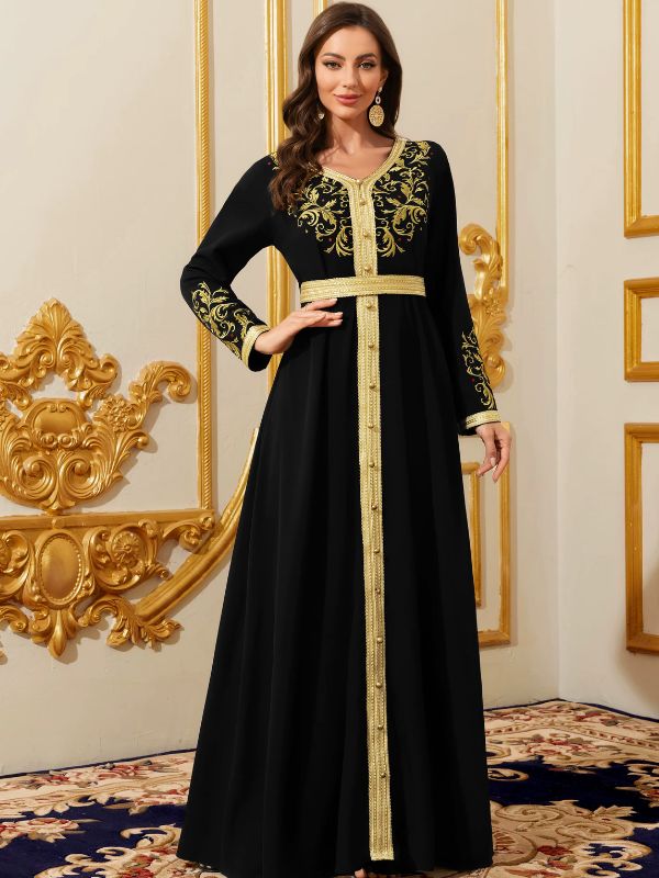 Femme en caftan marocain noir à broderies dorées et boutons sfifa, dans un intérieur baroque doré.