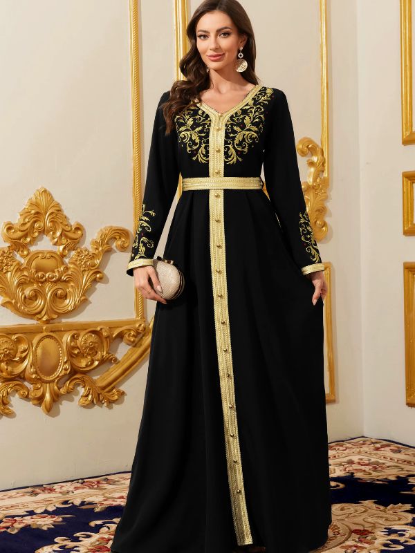 Une femme porte un sublime caftan noir et aux broderies or dans un intérieur subliment décorée en or