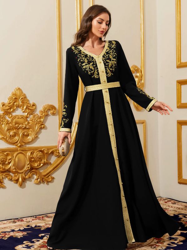 Femme en caftan marocain noir à broderies dorées et boutons sfifa, dans un intérieur baroque doré.