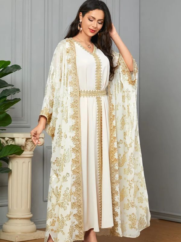 Une femme pose en caftan blanc fluide à broderies dorées