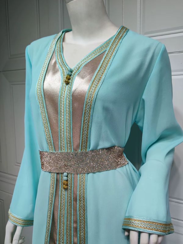 Gros plan sur les broderies dorées et turquoise qui ornent le devant du caftan menthe