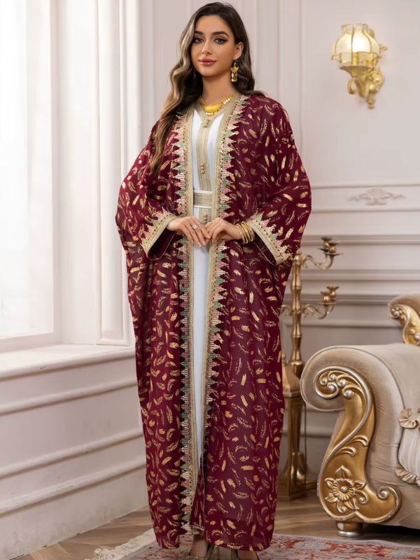 Une femme porte un caftan marocain bordeaux à motifs dorés