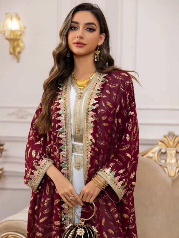 Une femme porte un caftan marocain bordeaux à motifs dorés