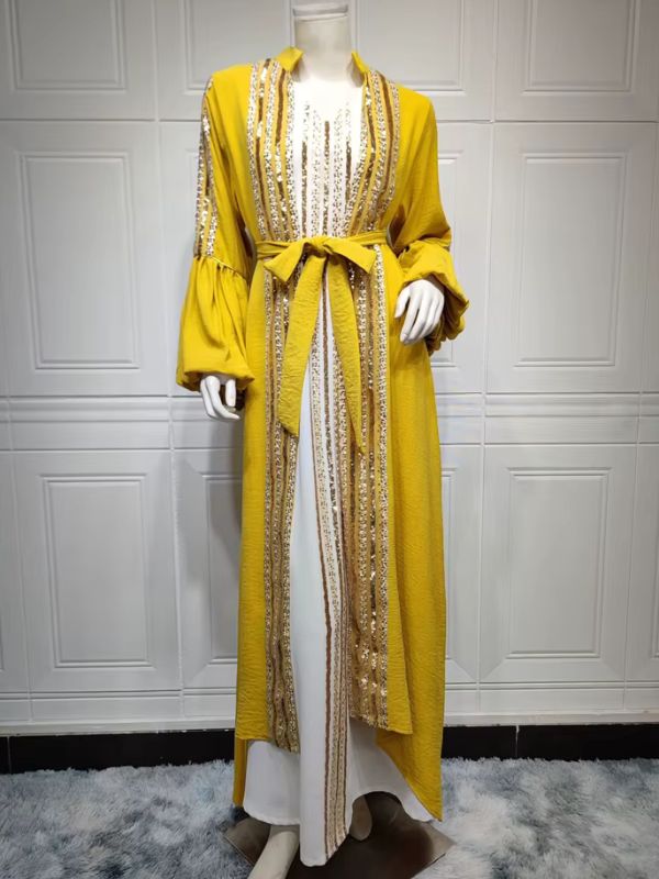 Caftan marocain jaune en pied sur mannequin, porté ouvert sur une robe blanche, avec broderies de sequins dorés.