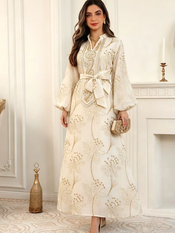 Femme portant le caftan marocain mariage crème brodé d'or, vue de face, ceinture nouée et pochette dorée