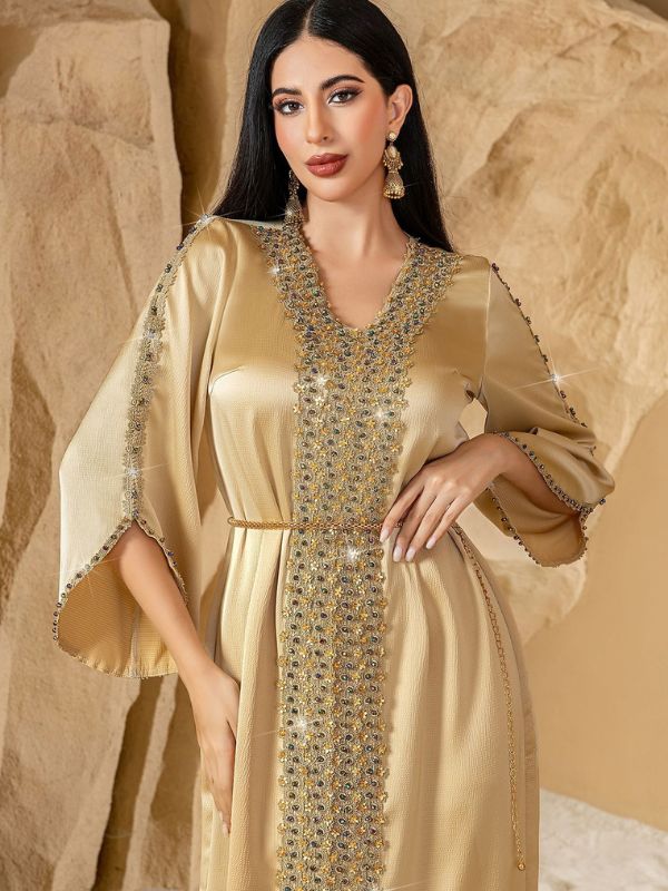 Caftan marocain mariage doré, main sur la hanche, bande centrale scintillante et ceinture chaîne dorée