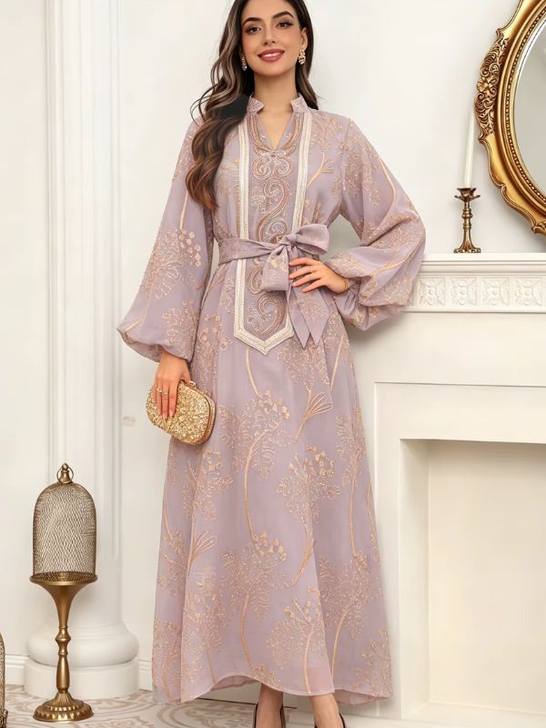 Caftan marocain mariage mauve porté, main sur la hanche, pochette dorée et manches ballon