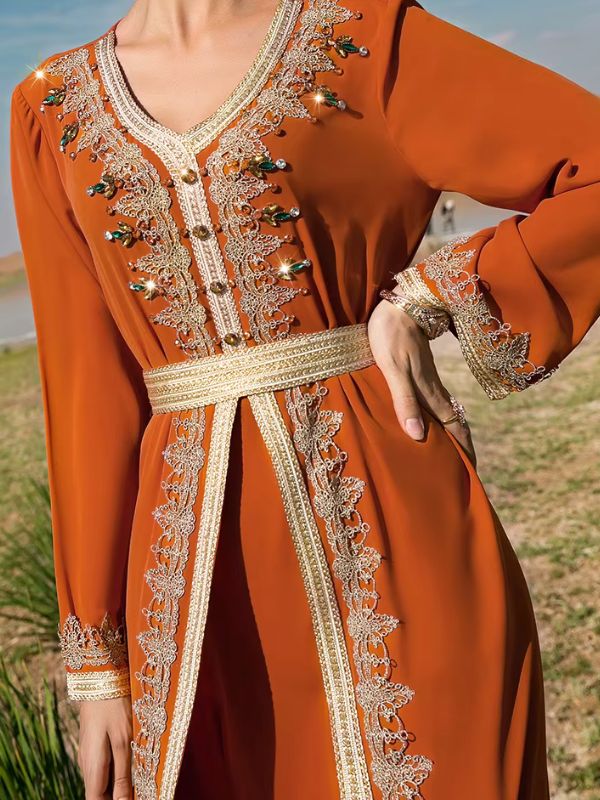 Détail du décolleté en V à boutons dorés, strass et dentelle, avec ceinture ruban doré sur le caftan marocain mariage orange