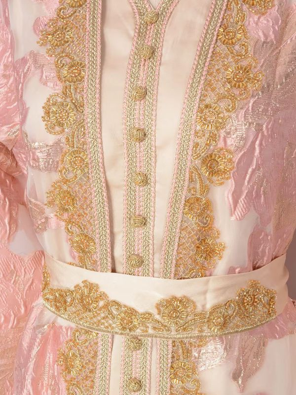 Détail du galon doré, des perles et de la ceinture satinée du caftan marocain mariage rose poudré
