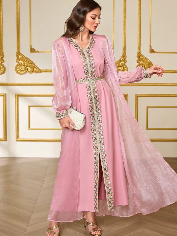 Caftan marocain rose Nacre de Tétouan de trois quarts, surcaftan irisé ouvert sur la robe rose à galon brodé, pochette en mise en scène