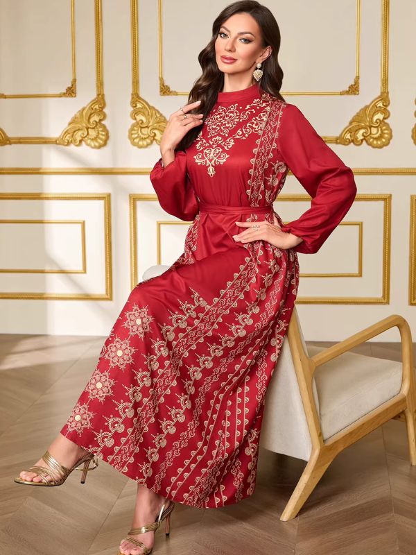 Femme assise portant le caftan marocain mariage rouge, jupe ample ornée de larges rosaces et de frises dorées
