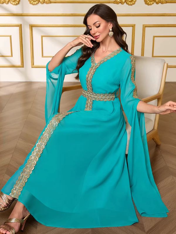 Femme assise portant le caftan marocain mariage turquoise, galon doré descendant le long de la jupe ample en mousseline