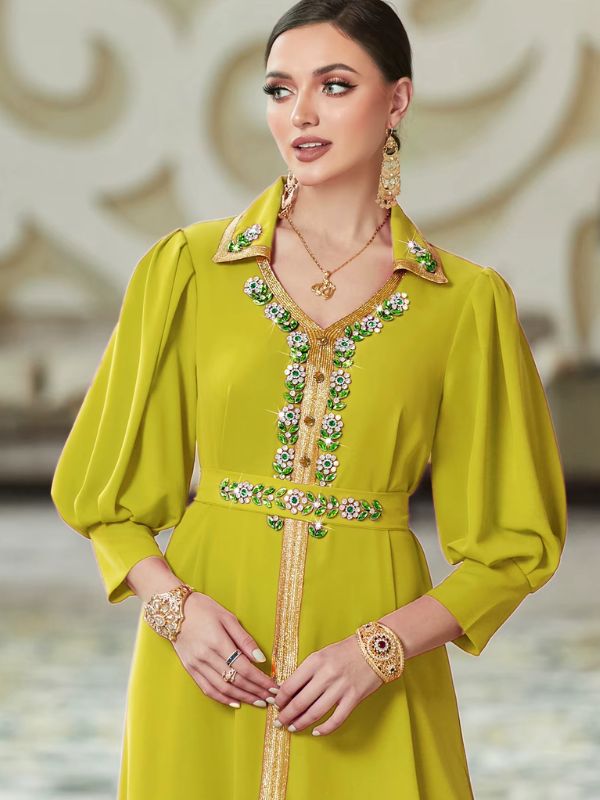Détail du col chemise doré et du décolleté en V orné de fleurs en strass verts et blancs sur le caftan marocain mariage vert anis