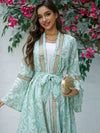 Une femme debout présente un caftan marocain fluide vert menthe