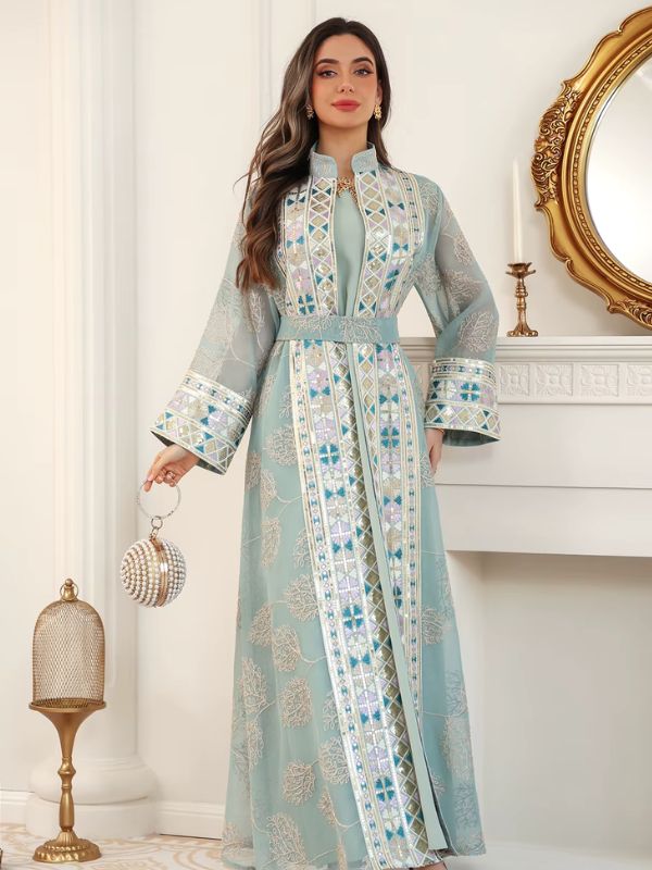 Femme en caftan turquoise à broderies andalouses, ceinturé à la taille, tenant une minaudière perlée.