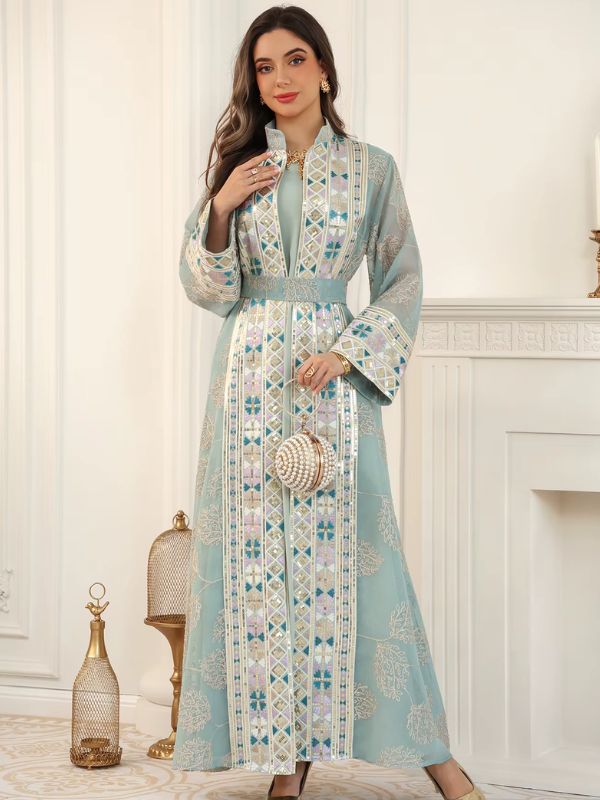 Femme en caftan turquoise brodé, tenant un sac boule perlé, dans un salon élégant.