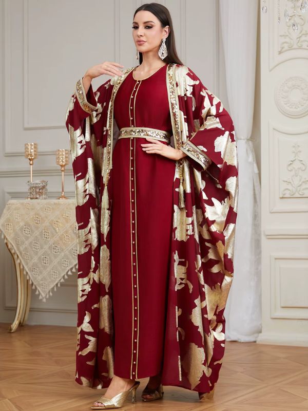 Femme portant un caftan marocain bordeaux avec cape à motifs dorés et ceinture ornée, vue de trois quarts