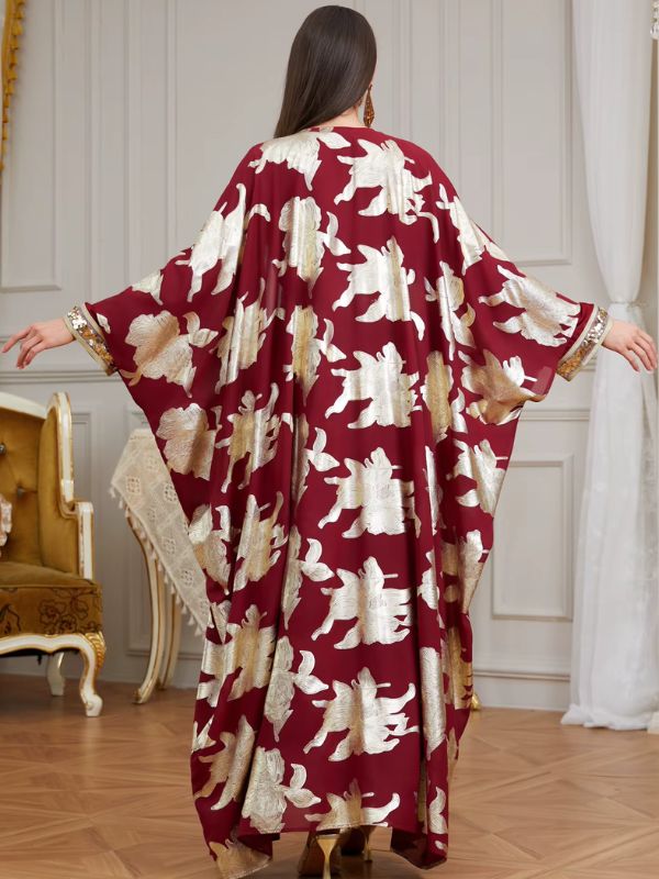 Femme de dos portant un caftan marocain bordeaux à motifs floraux dorés aux manches amples