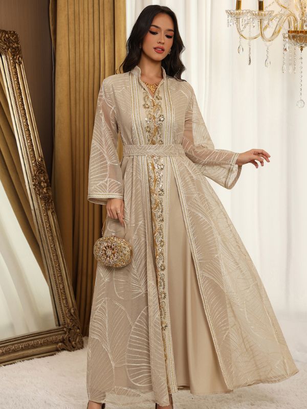 Femme portant un caftan ivoire en tulle brodé, porté ouvert sur une robe assortie, avec galon floral doré.