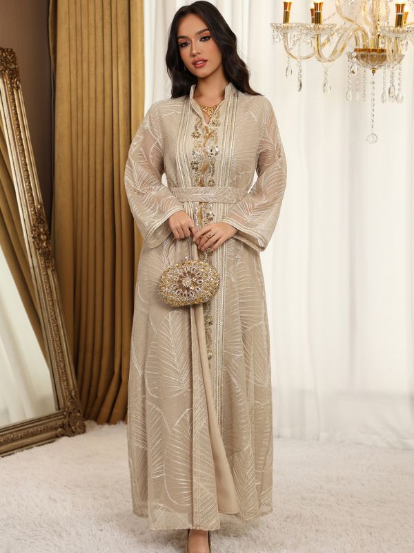 Femme portant un caftan ivoire en tulle brodé, porté ouvert sur une robe assortie, avec galon floral doré.