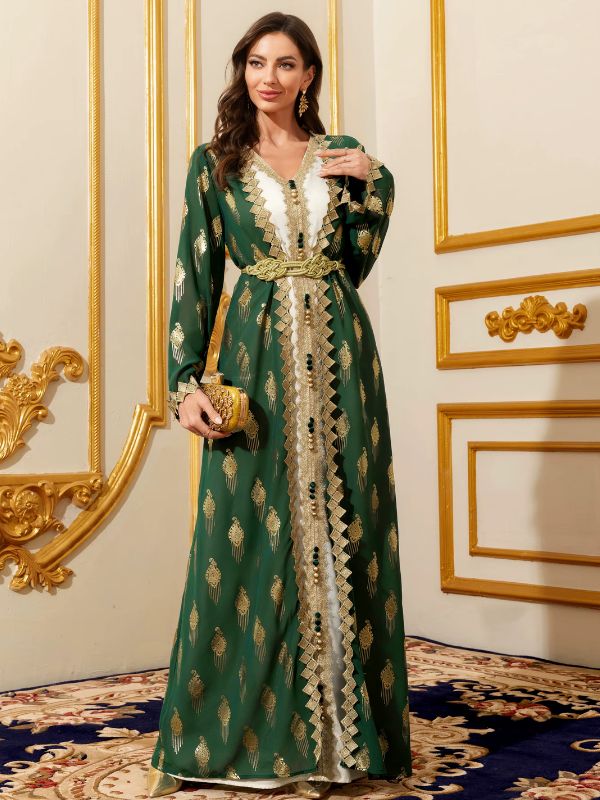 Femme portant un caftan marocain vert émeraude avec ceinture dorée, tenant une pochette assortie