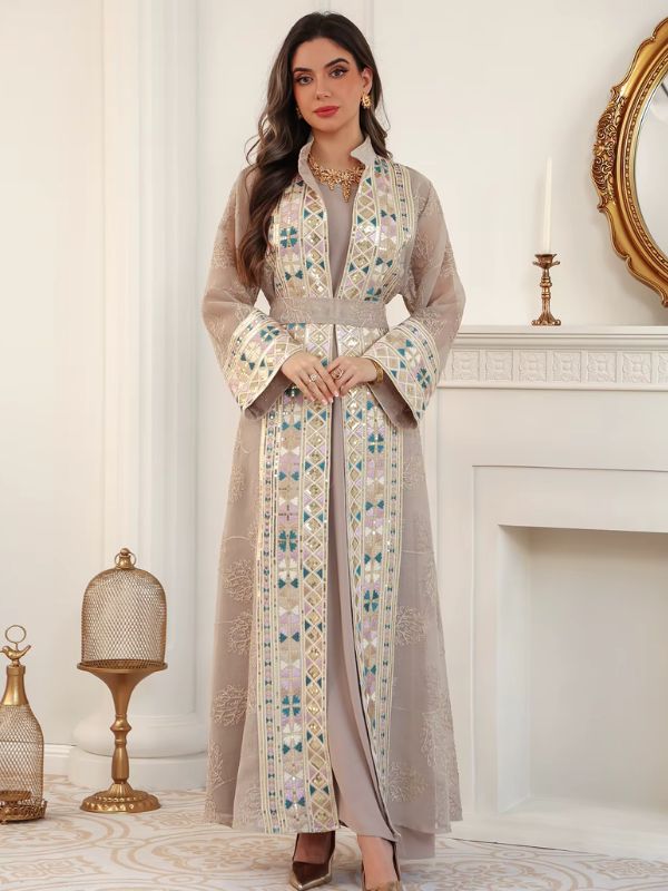 Femme portant un caftan champagne à broderies florales et bandes géométriques, dans un salon élégant.