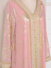 Zoom sur l’encolure brodée et les détails en perles et fils dorés d’un caftan marocain rose