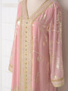 Détail du décolleté en V d’un caftan rose avec broderies dorées et boutons décoratifs