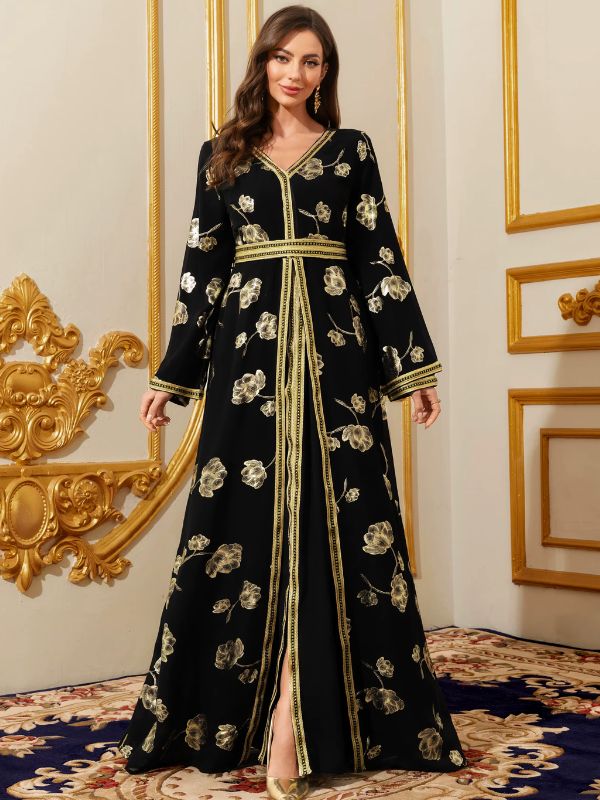 Femme portant un caftan marocain noir à fleurs dorées, fente centrale et fines bordures dorées, avec des escarpins assortis