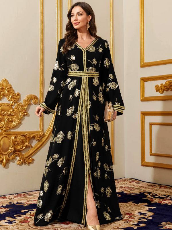 Femme portant un caftan marocain noir à fleurs dorées, pochette scintillante à la main, dans un intérieur élégant