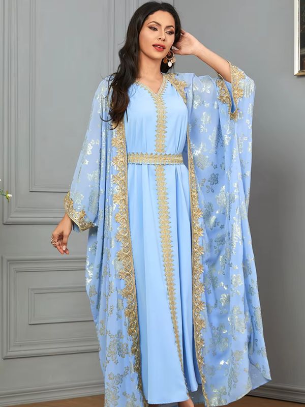 Une femme debout en caftan bleu fluide avec des ornements dorés
