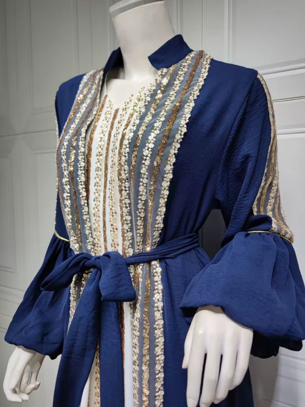Vue de trois quarts d'un caftan marocain bleu royal, orné de bandes de sequins dorés et ceinture nouée.