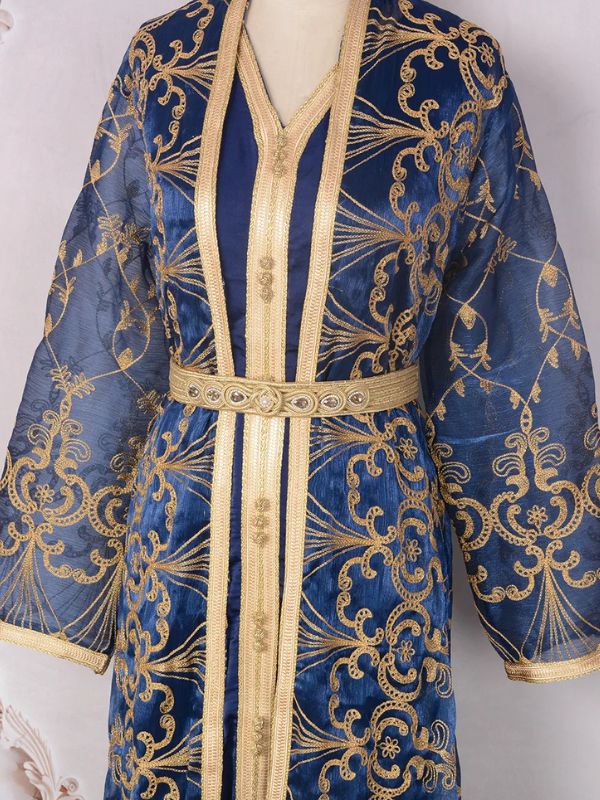 Mannequin vêtu d’un caftan marocain bleu nuit richement brodé posé avec grâce à l’extérieur