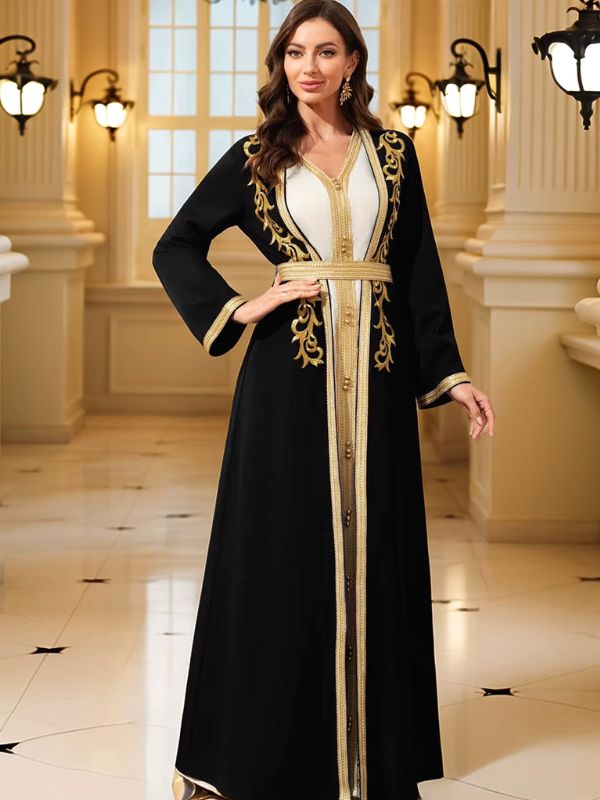 Femme souriante portant un caftan marocain noir et blanc à galons dorés, main sur la hanche