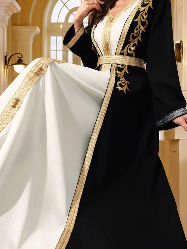 Détail d'un caftan marocain noir déployé sur robe blanche, bordures dorées brodées