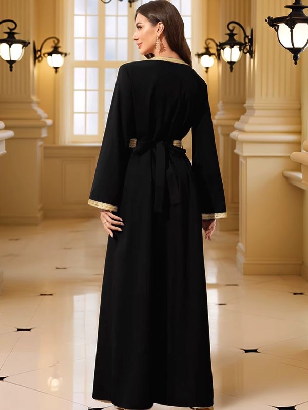 Femme de dos portant un caftan marocain noir à liserés dorés avec ceinture nouée