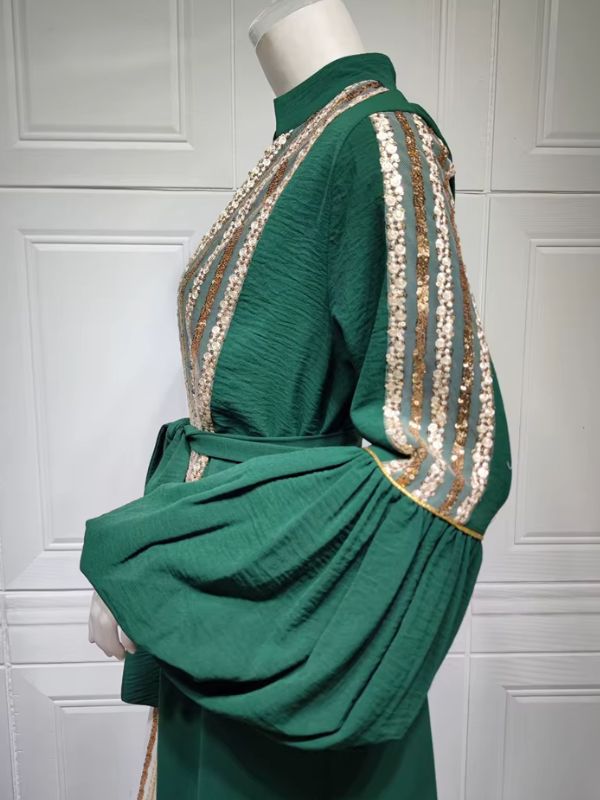 Vue de profil d'un caftan vert émeraude, manches bouffantes ornées de rangées de sequins dorés.