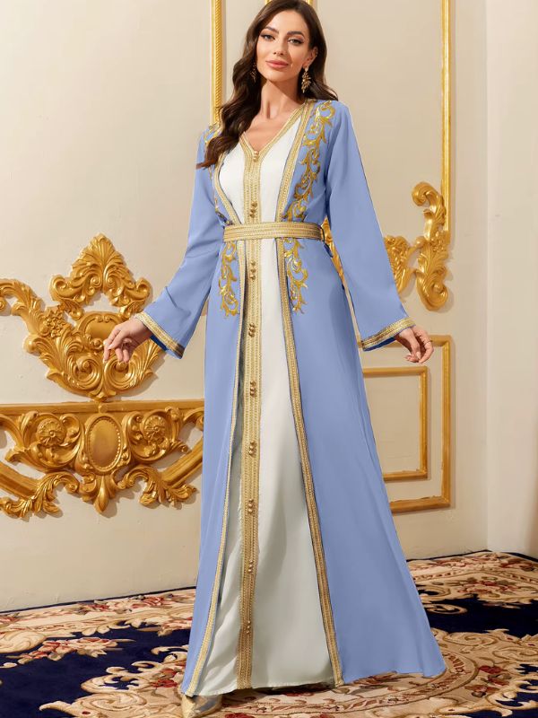 Femme en caftan marocain azur et blanc aux broderies dorées, ceinture galonnée, posant dans un décor luxueux