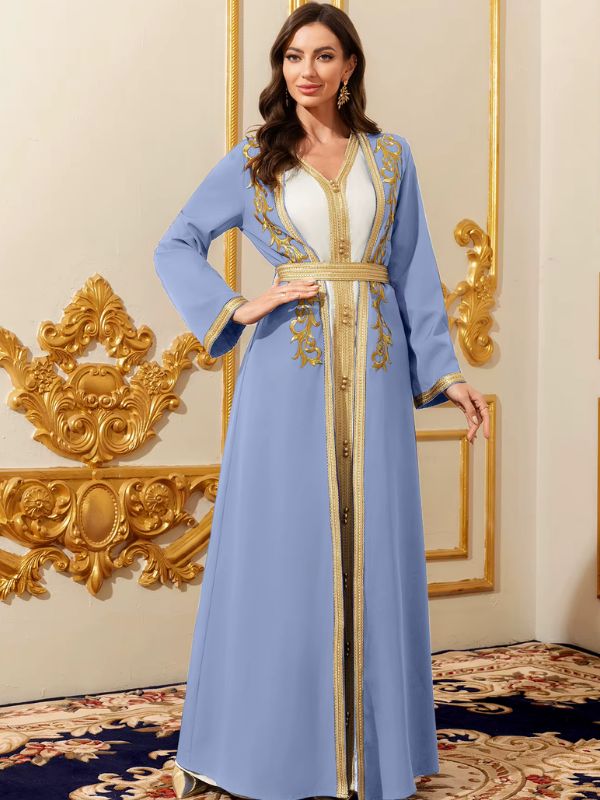 Femme en caftan marocain azur et blanc aux broderies dorées, ceinture galonnée, posant dans un décor luxueux