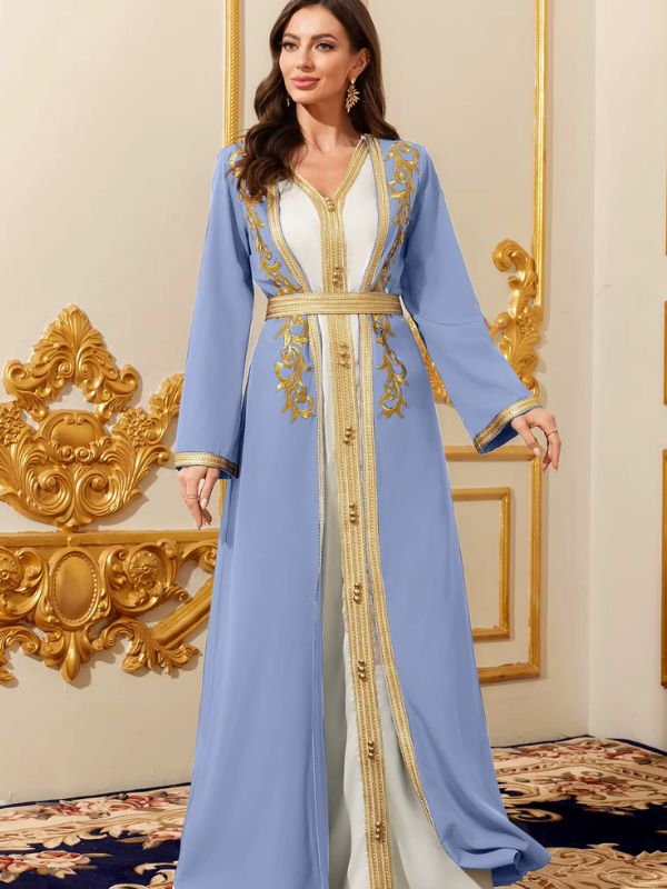 Femme portant un caftan marocain azur superposé sur une robe blanche, broderies dorées et ceinture assortie, dans un intérieur élégant
