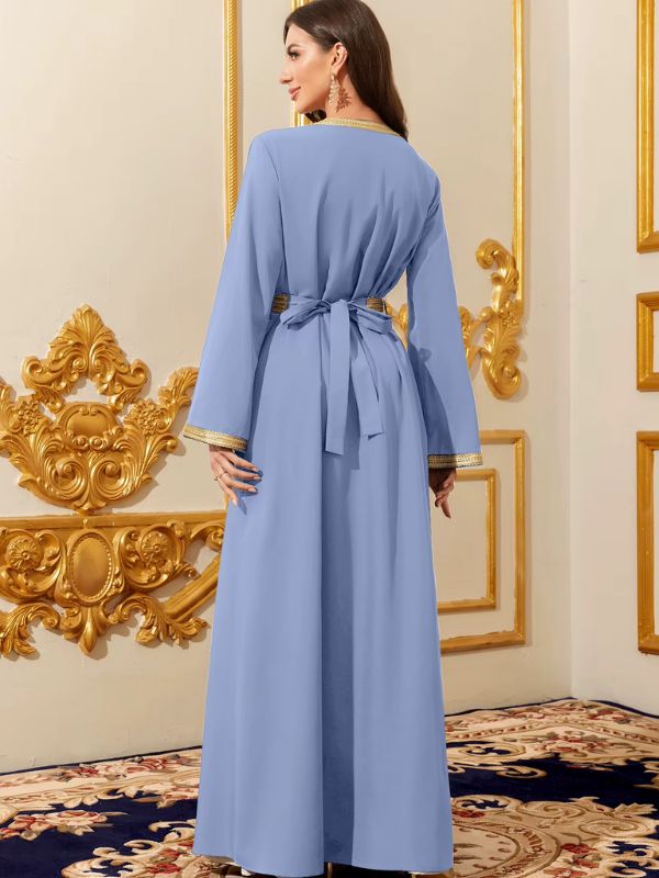 Caftan marocain bleu azur vu de dos, ceinture nouée et poignets bordés de galon doré, dans un décor doré raffiné