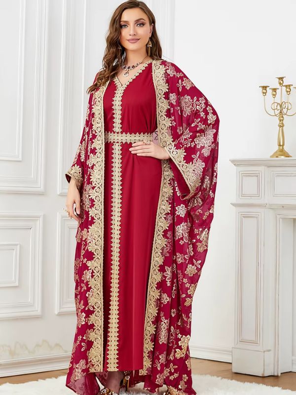 Une femme debout en caftan bordeaux orné de broderies dorées